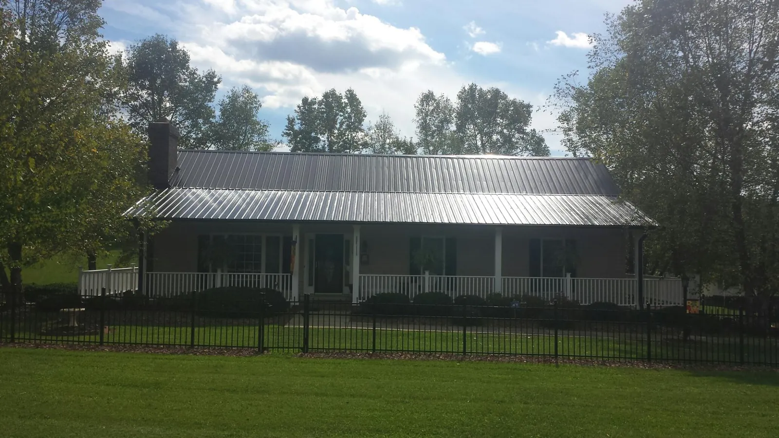 Gray metal roof on a brick ranch with a full width front porch — Gutter Guard Installation work by our crew in Deerfield
